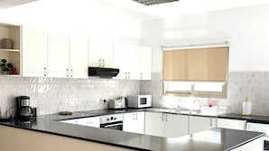 Cozinha moderna com armários brancos, bancada preta e fogão embutido.