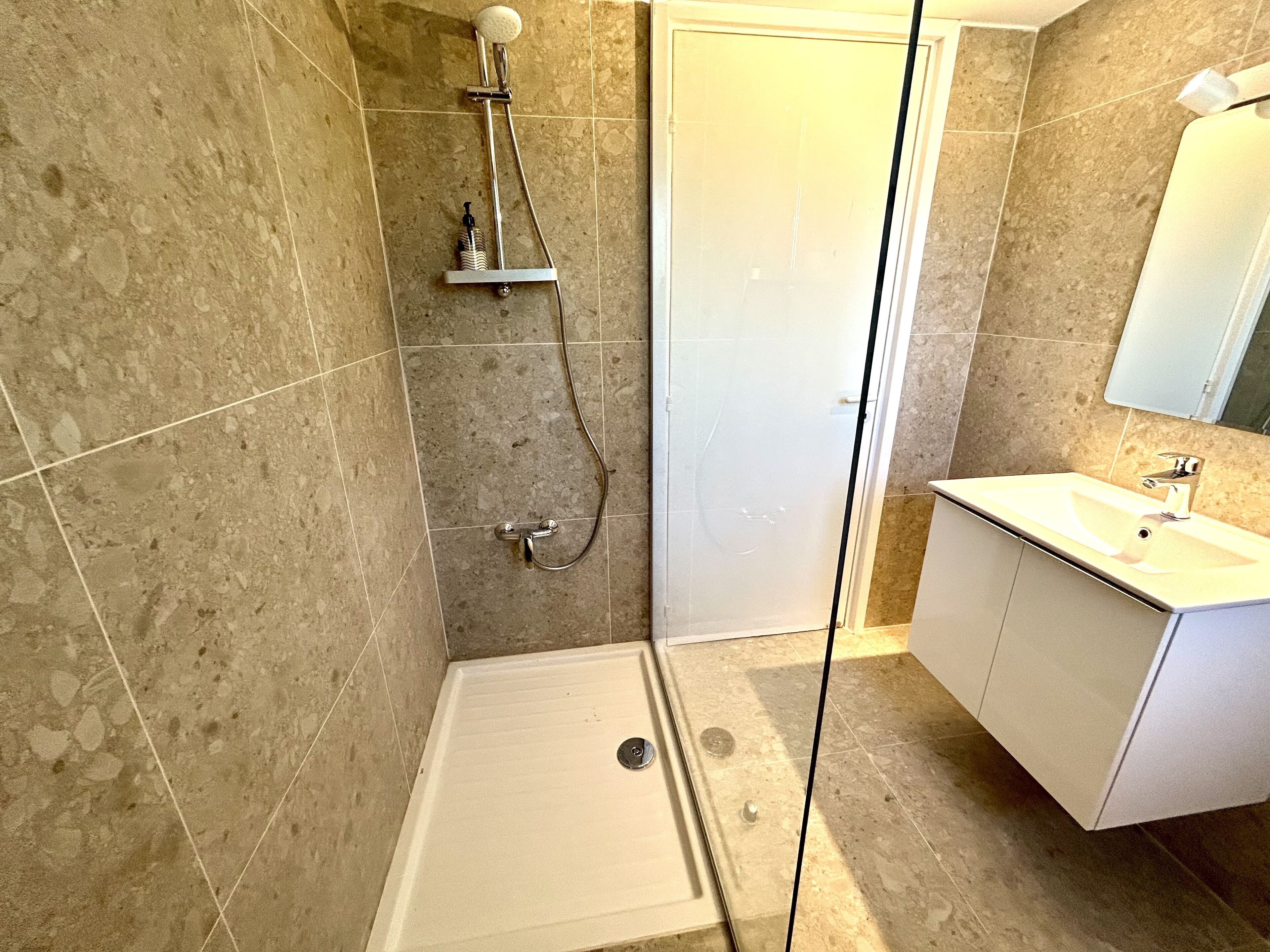 Un baño con ducha, lavamanos y espejo.