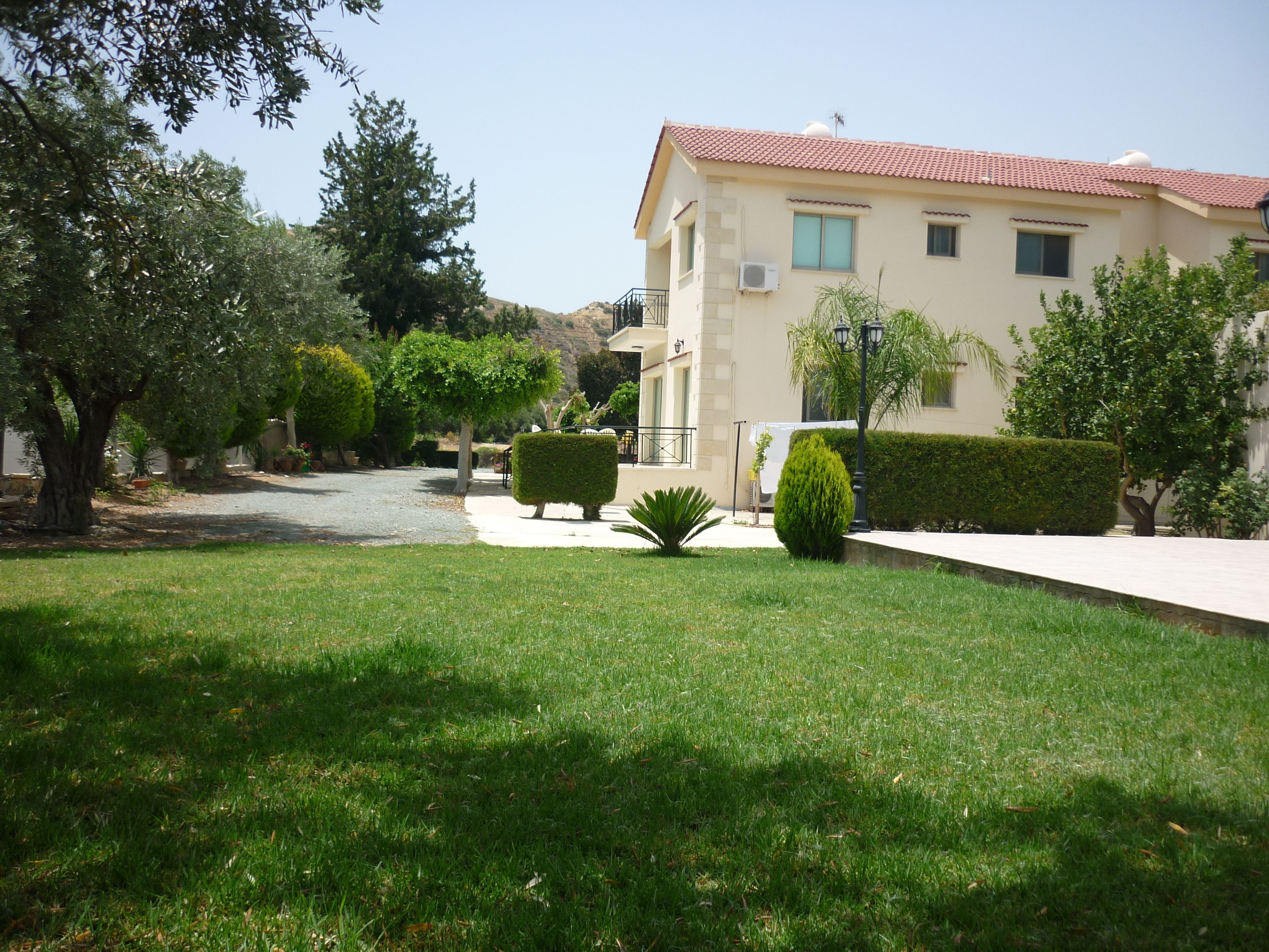 A residential area with a well-maintained lawn, neatly trimmed hedges, and a building with a tiled roof.