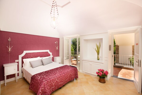 A bedroom with a bed, bedside tables, a hanging light fixture, a window with a view of the outdoors, and a potted plant. - Villa Don Camillo Relais (Sant'Agnello)