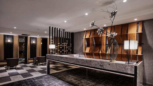 A modern reception area with a check-in counter, seating, and decorative elements like a vase with flowers. - Unababy Hotel (Hengchun)