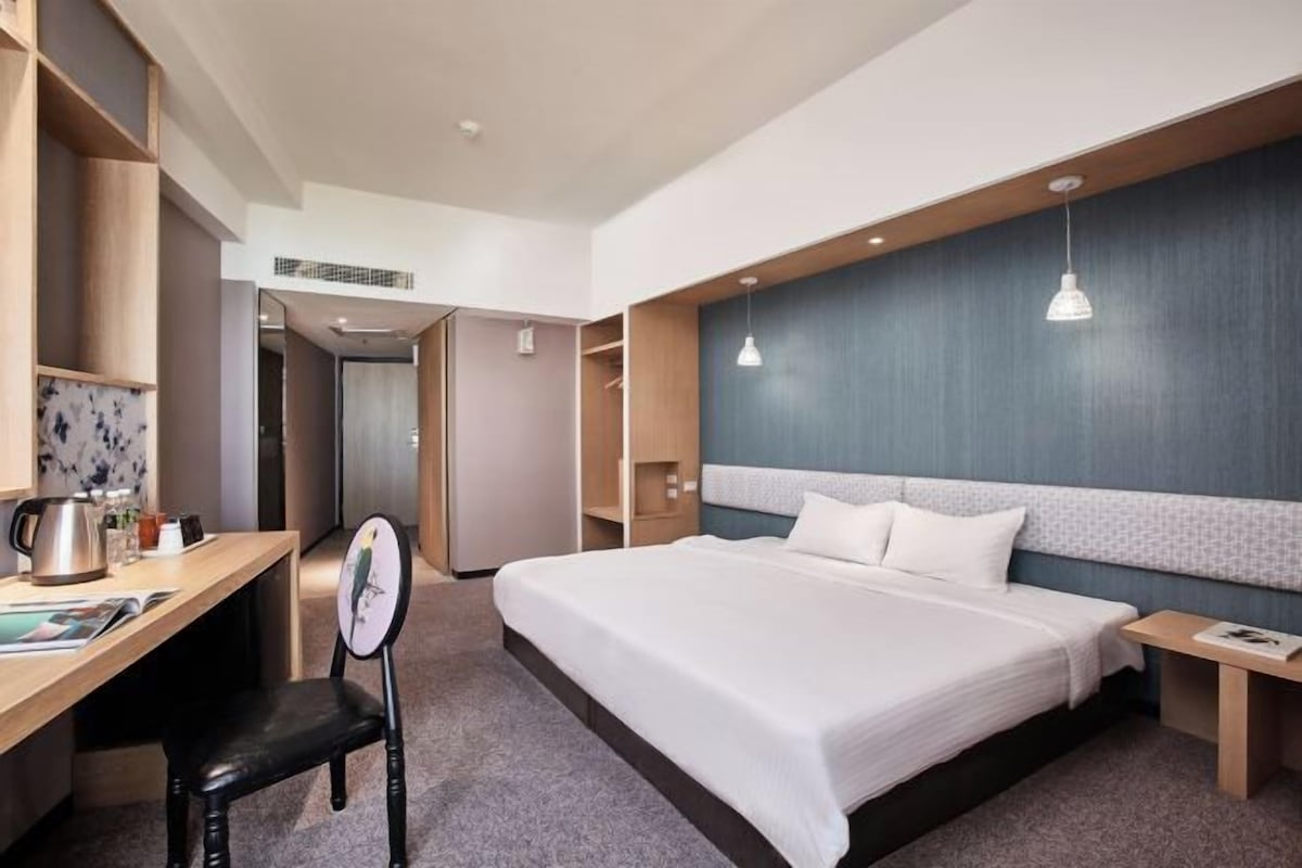 Una habitación de hotel moderna con una cama grande, un escritorio con una silla y un armario.