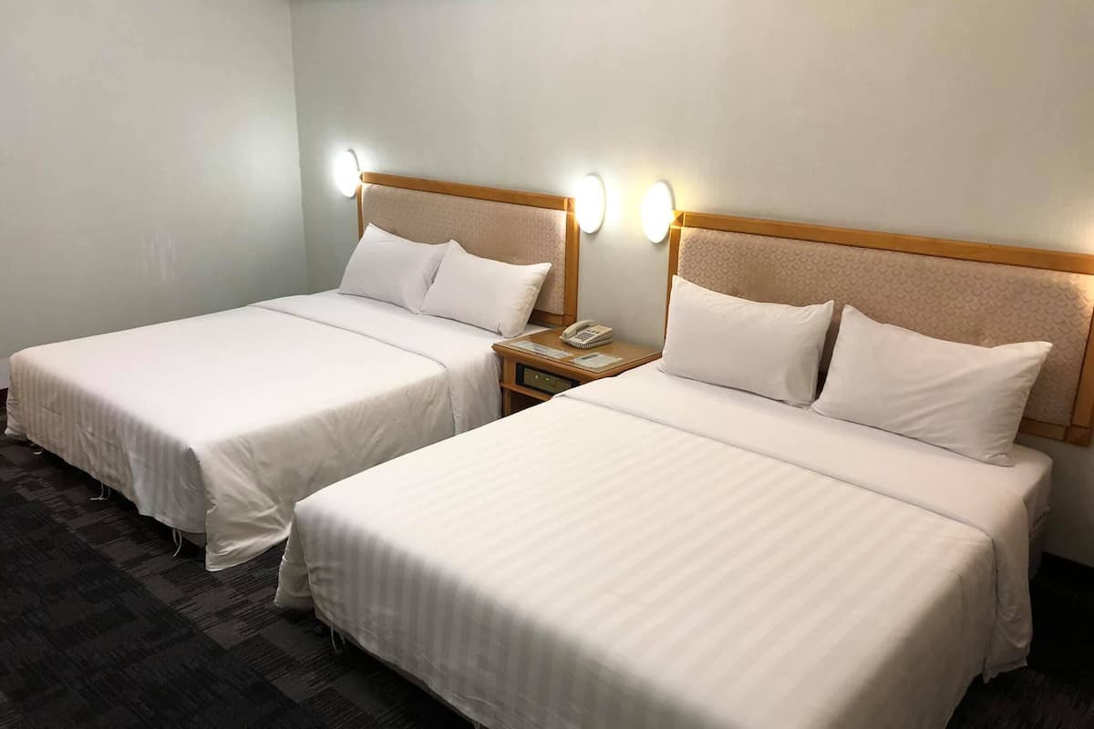 Two single beds with headboards, a bedside table with a phone, and wall-mounted lights.