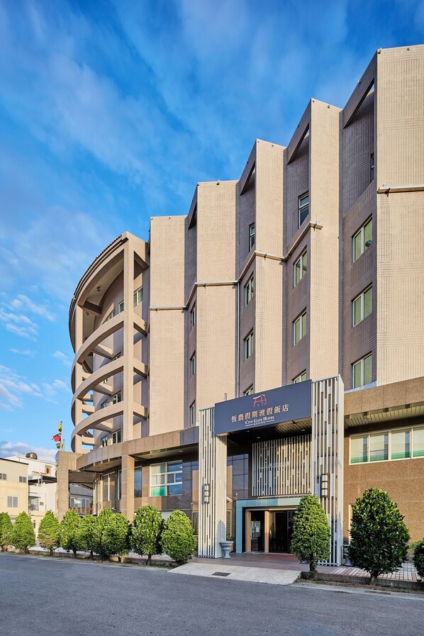 A modern hotel with a curved facade, multiple floors, and a prominent entrance. - Unababy Hotel (Hengchun)