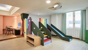 A children's play area with a slide, colorful steps, and a desk with a chair. - Unababy Hotel (Hengchun)