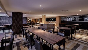 A modern restaurant with wooden tables and chairs, a bar area, and a patterned wall. - Unababy Hotel (Hengchun)