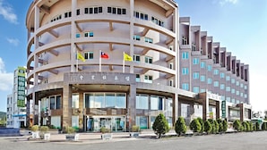 A multi-story hotel with a curved facade, multiple balconies, and a prominent entrance with glass doors. - Unababy Hotel (Hengchun)