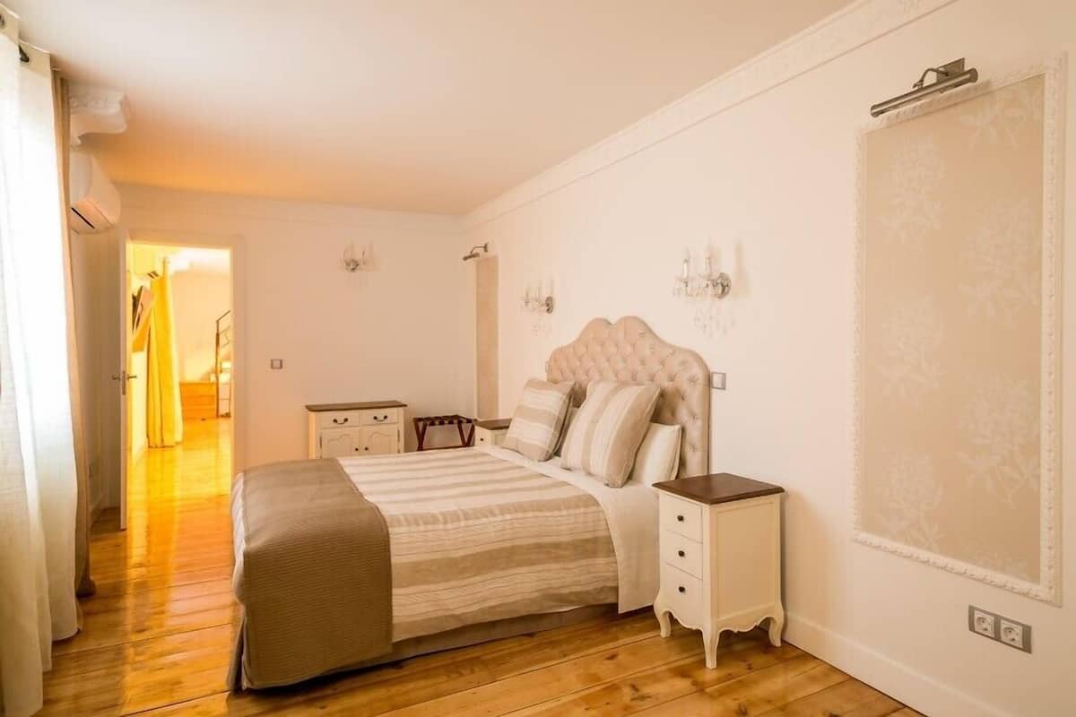 Un dormitorio con una cama grande, mesitas de noche, un armario y un espejo.