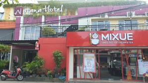 Un bâtiment abritant un magasin de glaces et de boissons Mixue, un scooter garé et une enseigne indiquant un hôtel appelé « Nutanahotel ».