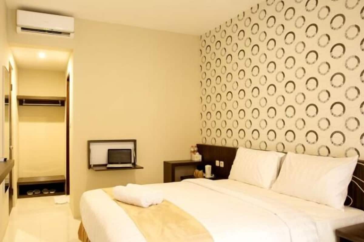 Habitación de hotel con cama, televisor, escritorio y aire acondicionado de pared.