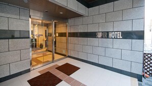 Der Eingang zum Super Hotel, modern gestaltet, mit Glastür und Schild.