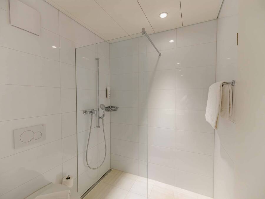 A modern bathroom with a glass shower enclosure, a toilet, and a towel rack.