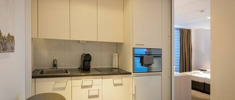 A compact kitchen with a sink, coffee maker, and a small refrigerator.