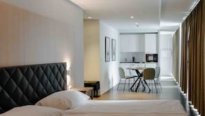A hotel room with a bed, a desk, and a kitchenette.