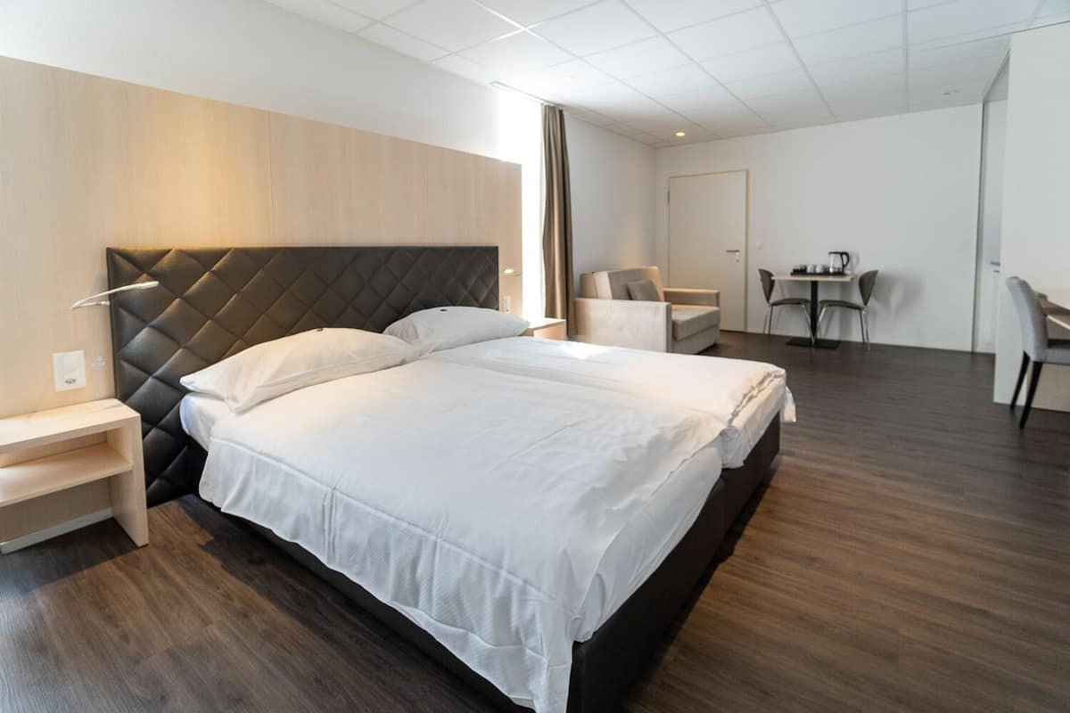 Moderni hotellihuone, jossa on suuri sänky, yöpöydät, työpöytä ja tuoli.