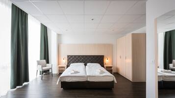 Una habitación de hotel moderna con una cama grande, dos mesitas de noche, una silla y un armario.