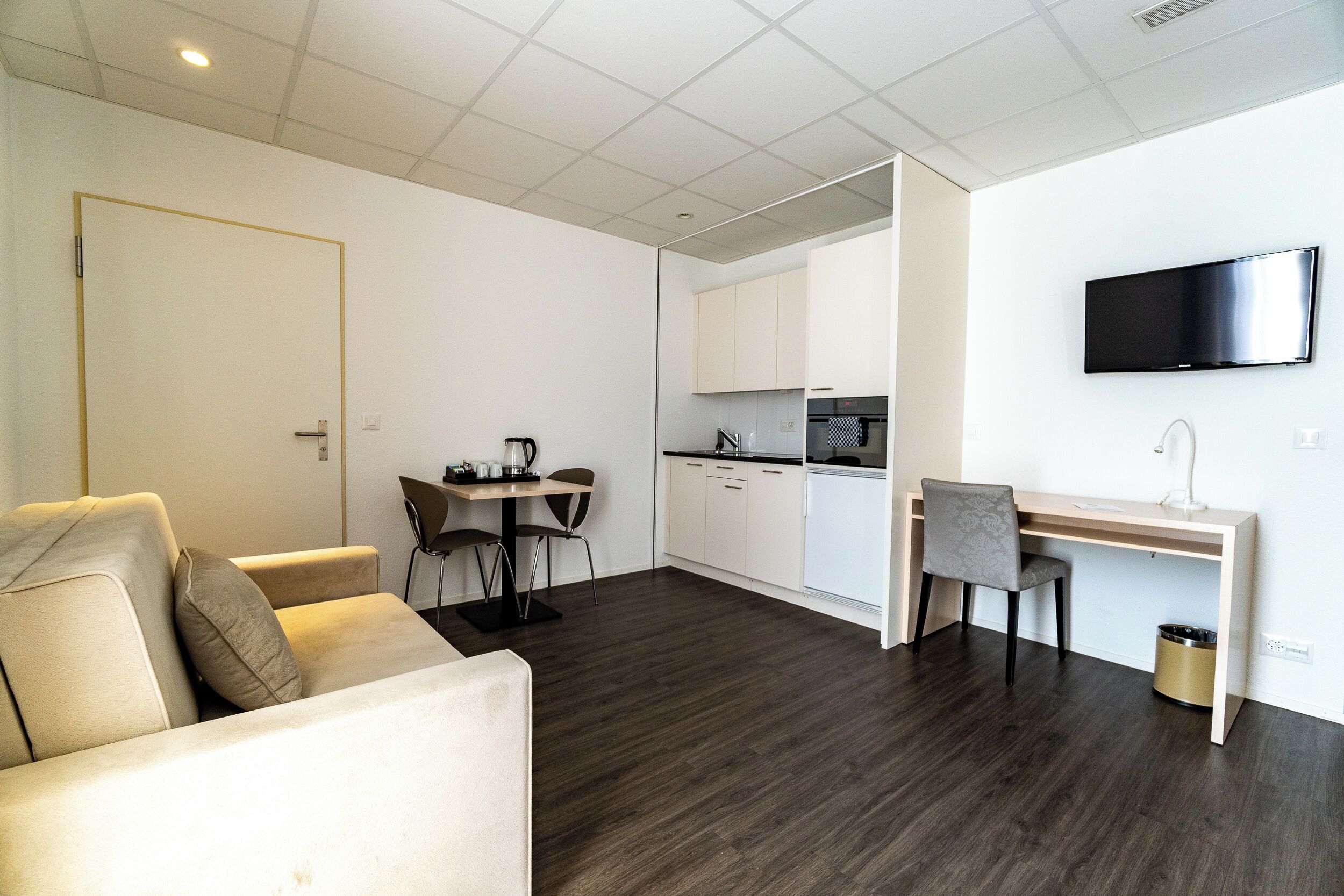 Eine moderne Wohnung mit Wohnbereich, Esstisch, Küche und Schreibtisch.