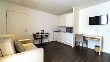 Eine moderne Wohnung mit Wohnbereich, Esstisch, Küche und Schreibtisch.