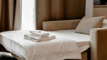 Habitación de hotel con cama, una silla, una mesita y una ventana con cortinas.