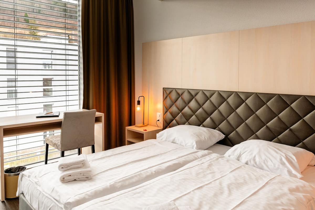 Hotellihuone, jossa on suuri sänky, työpöytä ja tuoli.