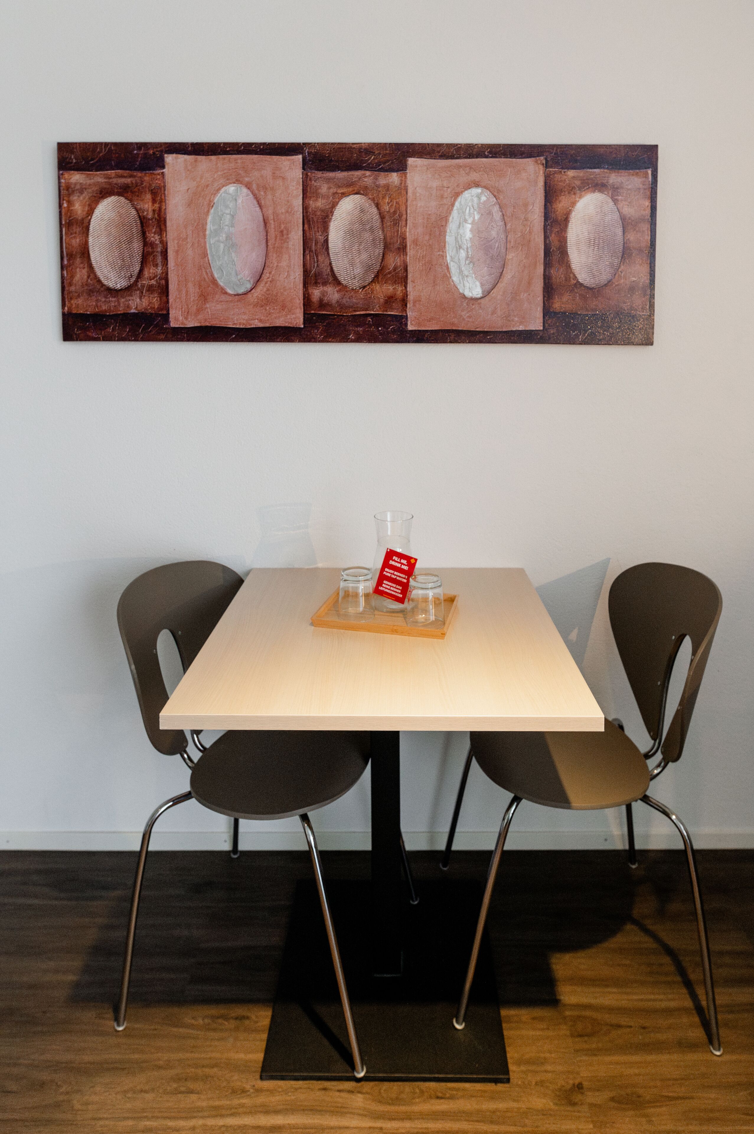 Un comedor con una mesa, dos sillas y una obra de arte colgada en la pared.