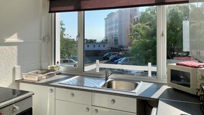 Una cocina con un ventanal grande, un lavaplatos y un microondas.