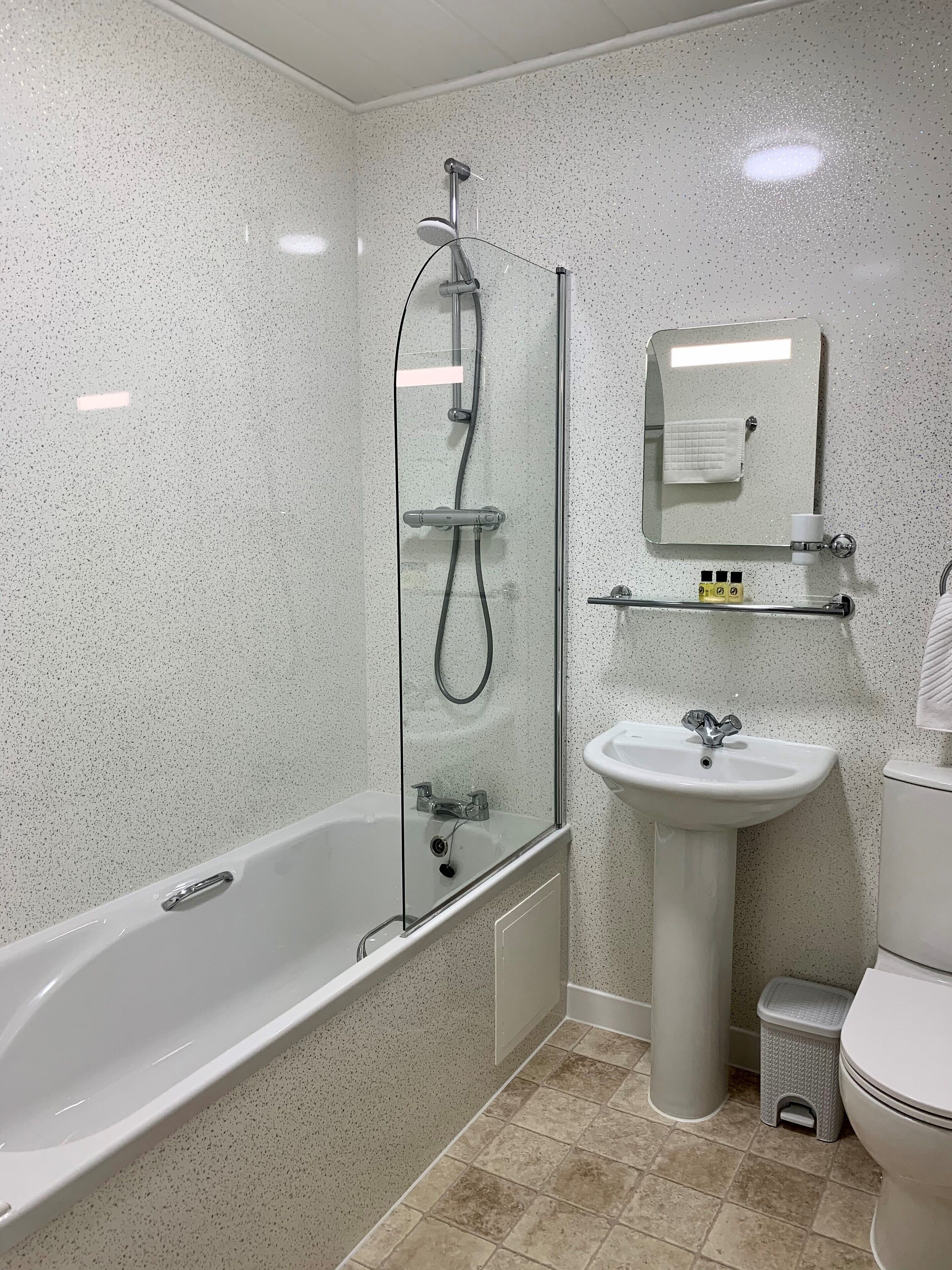 A bathroom with a glass-enclosed shower, a pedestal sink, and a toilet.