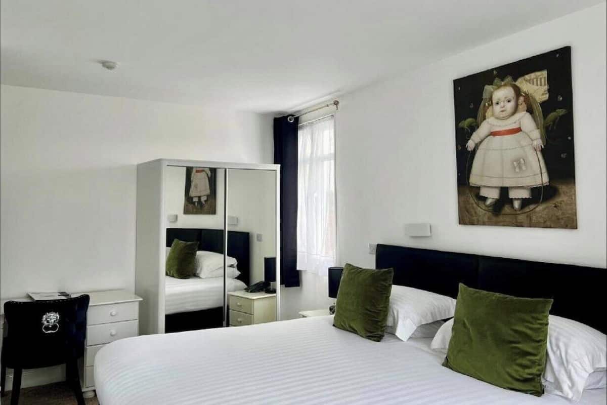Habitación de hotel con una cama grande, un armario, un escritorio y un cuadro en la pared.