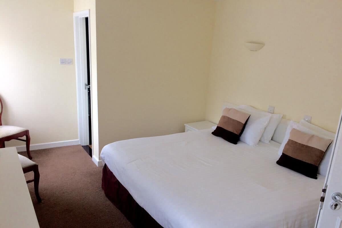A hotel room with a large bed, a desk, and a chair.
