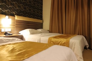 A hotel room with two beds, a headboard, a nightstand with a lamp, and a curtain. - Clover Hotel (Masai)