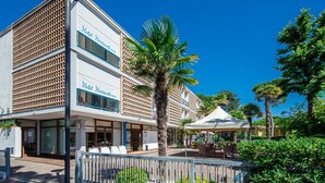 Un hotel con fachada moderna, ventanas amplias y una zona de estar exterior cubierta.