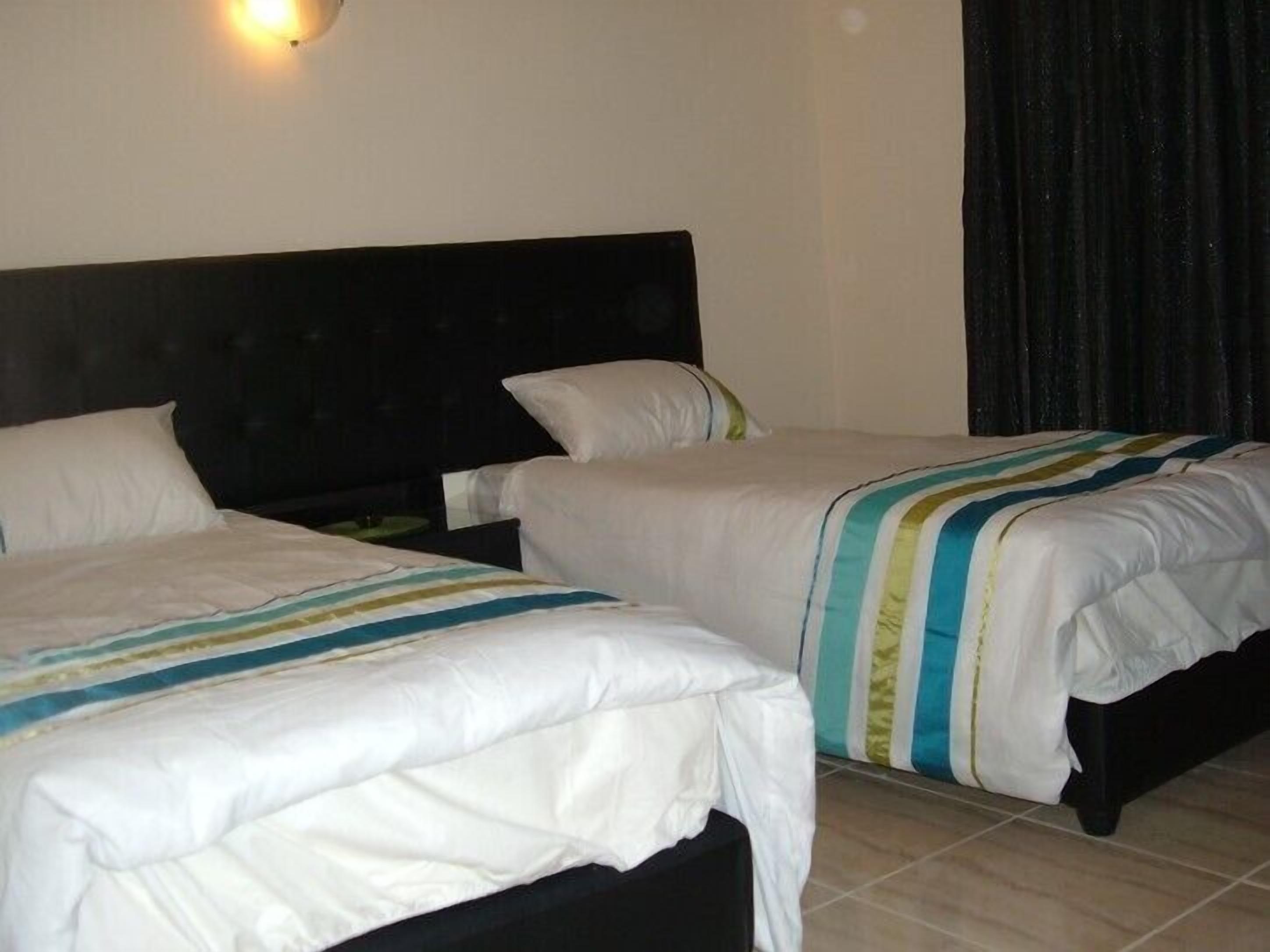 A hotel room with two beds, each with white bedding and striped blankets.