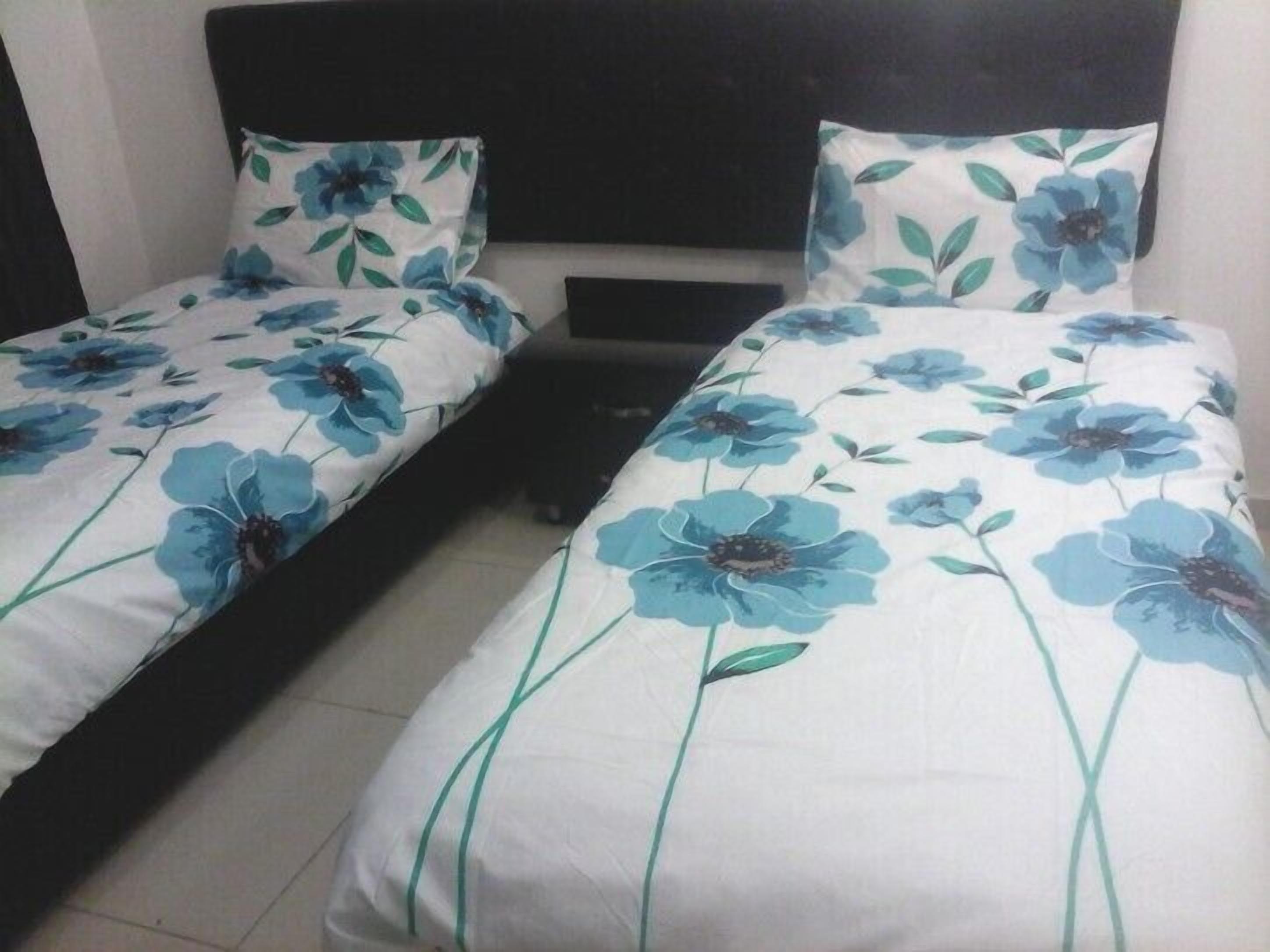 Une chambre avec deux lits simples, chacun agrémenté d’une couvre-lit à motifs floraux et de coussins assortis.