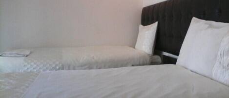A hotel room with two beds, each with white bedding and pillows.