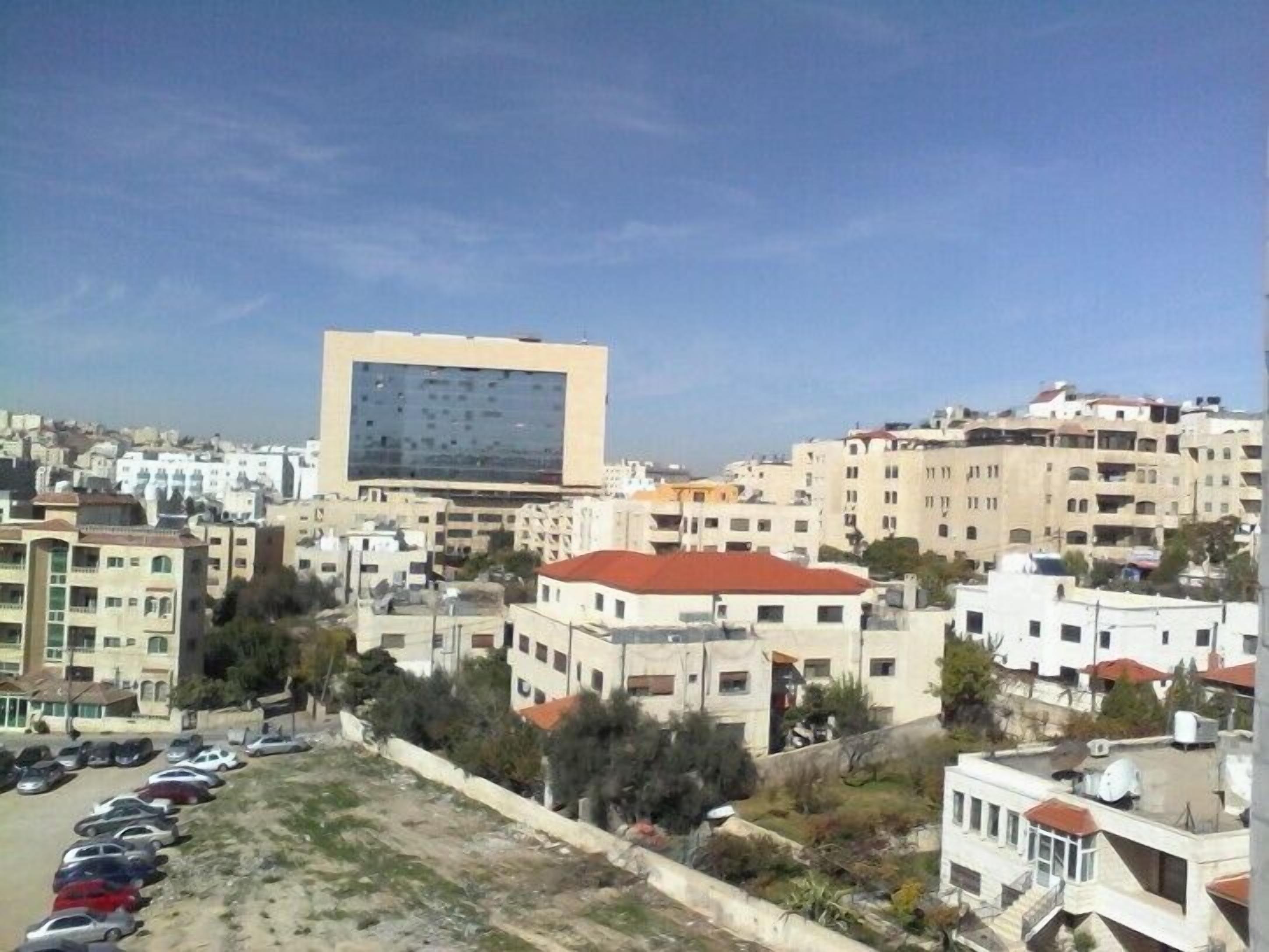 Une vue urbaine mettant en valeur un bâtiment moderne imposant, doté d’une façade en verre réfléchissant.