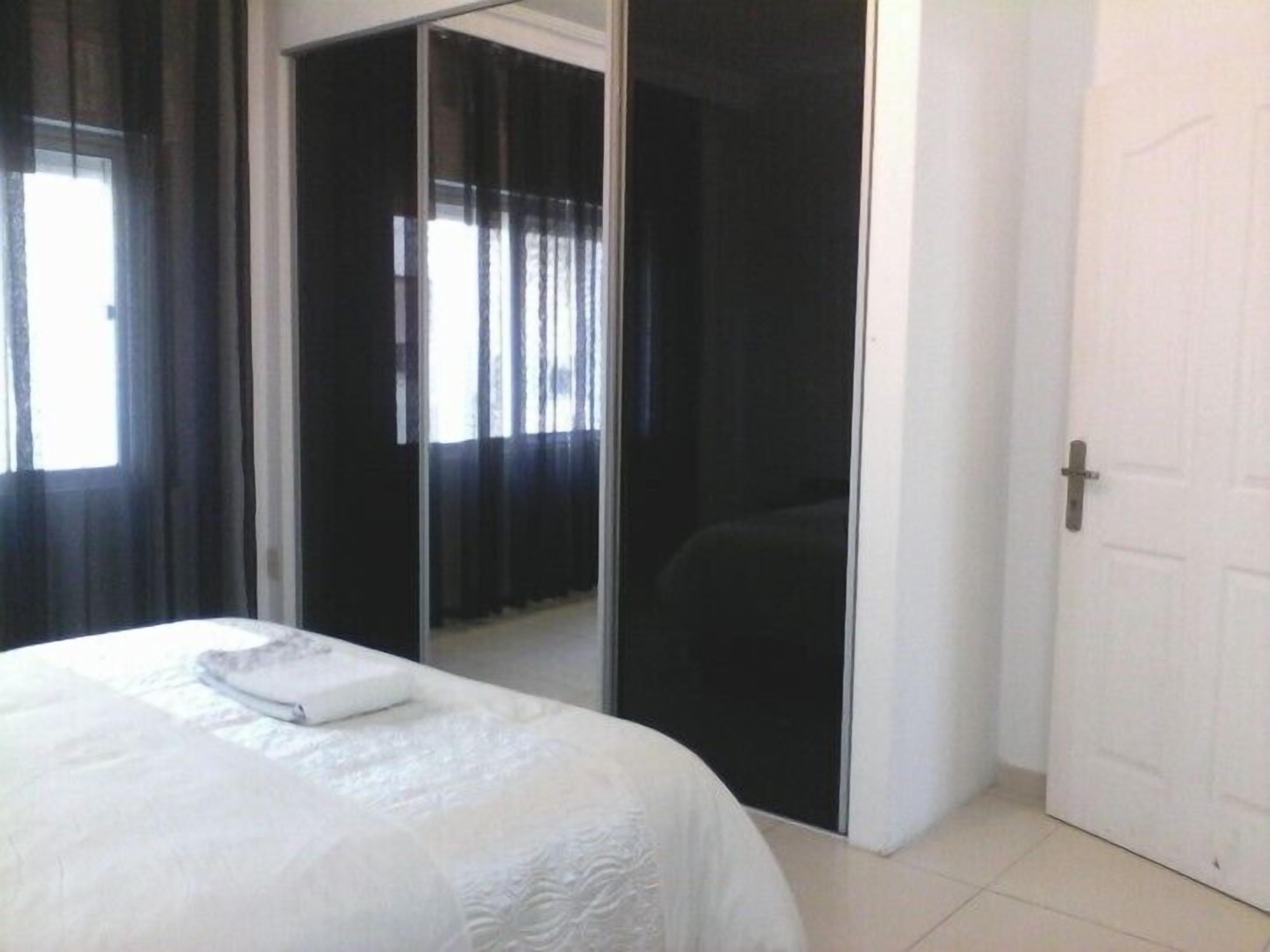 A bedroom with a bed, a sliding door closet, and a window with curtains.