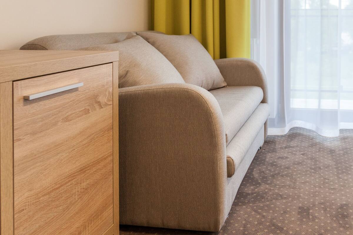 A room with a sofa, a wooden cabinet, and a patterned carpet.