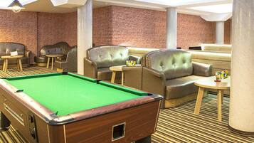 Une salle de billard équipée d’une table de billard, de canapés en cuir et de petites tables.