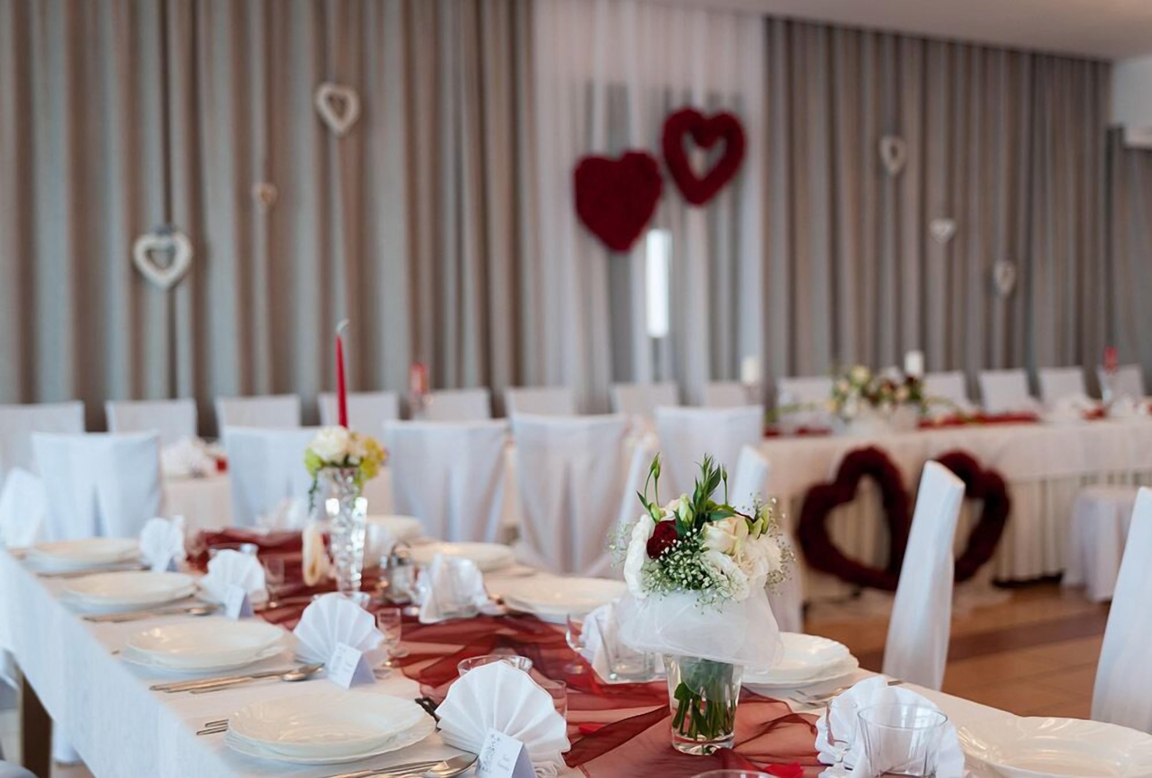 A banquet hall with tables set for a formal event, featuring white tablecloths, glassware, and floral centerpieces.