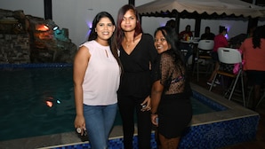 Tres personas junto a una piscina con un muro de piedra y un borde con baldosas.