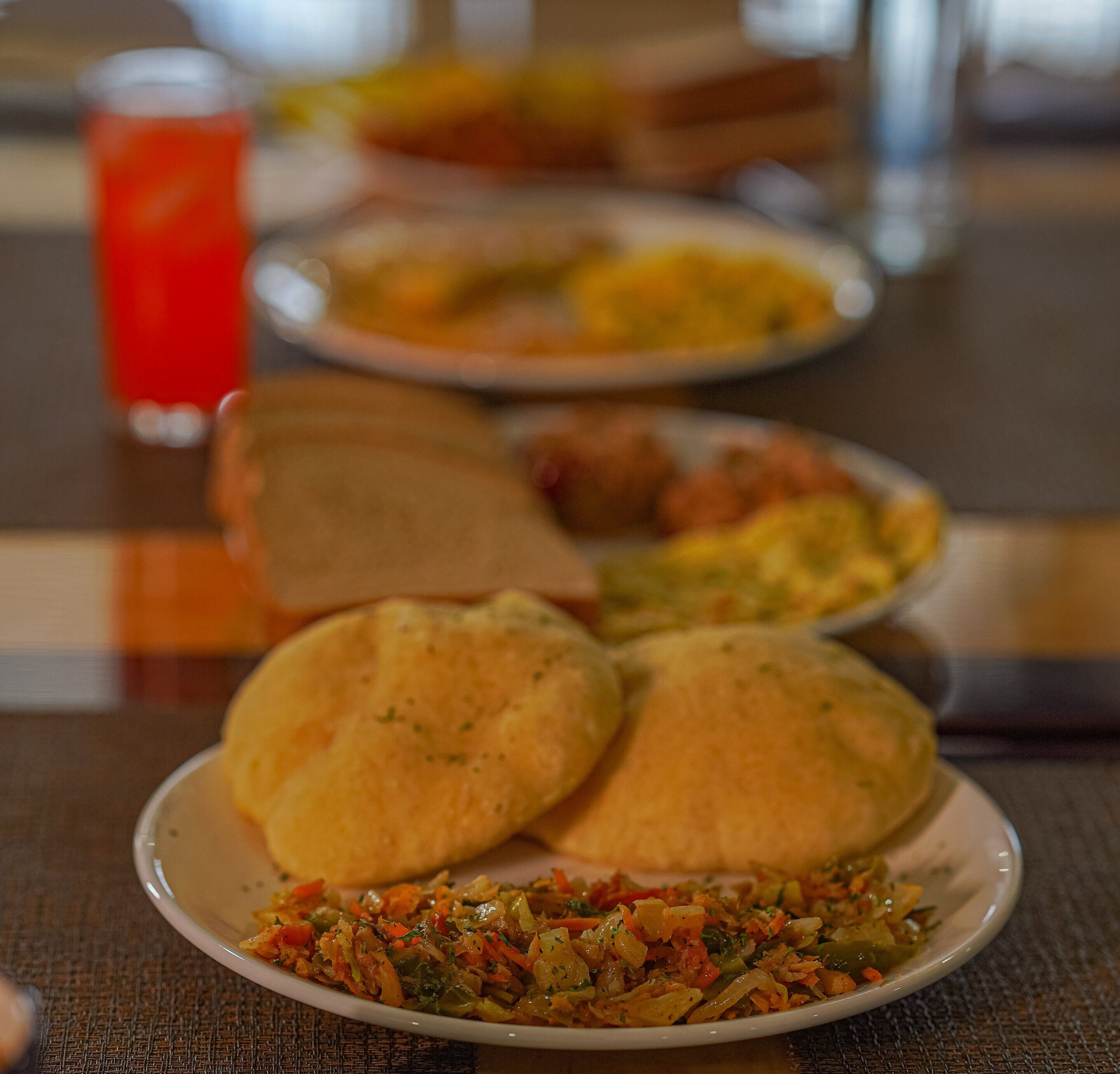 Uma mesa de jantar com pratos de comida, incluindo um prato de legumes e pão.