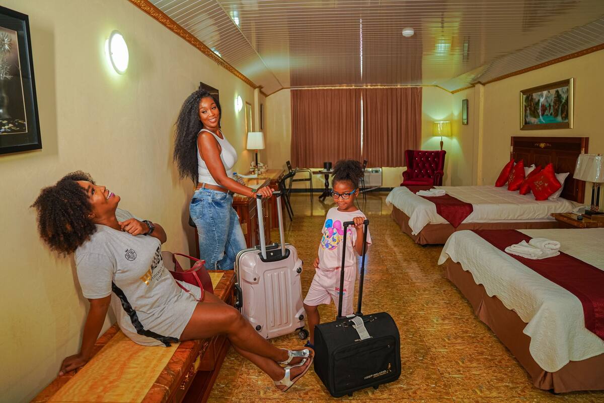 A hotel room with two beds, a sitting area, a dining table, and a large window.