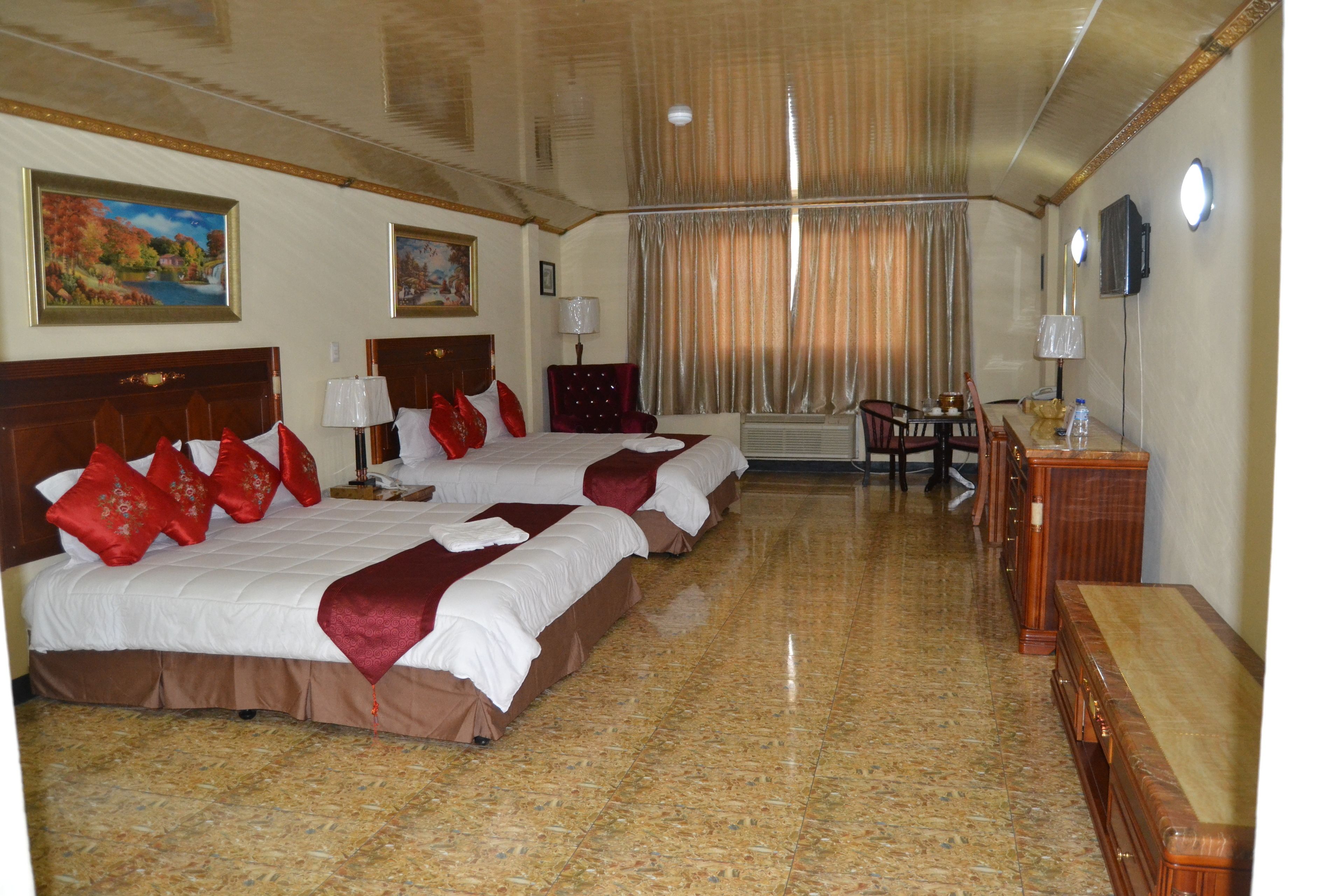 Une chambre d’hôtel avec deux lits, un bureau et une chaise.