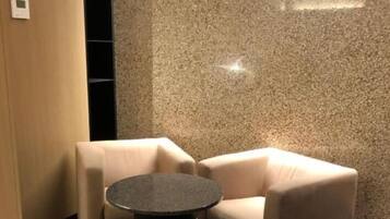 Un rincón de una habitación con dos sillones color beige y una mesa redonda.