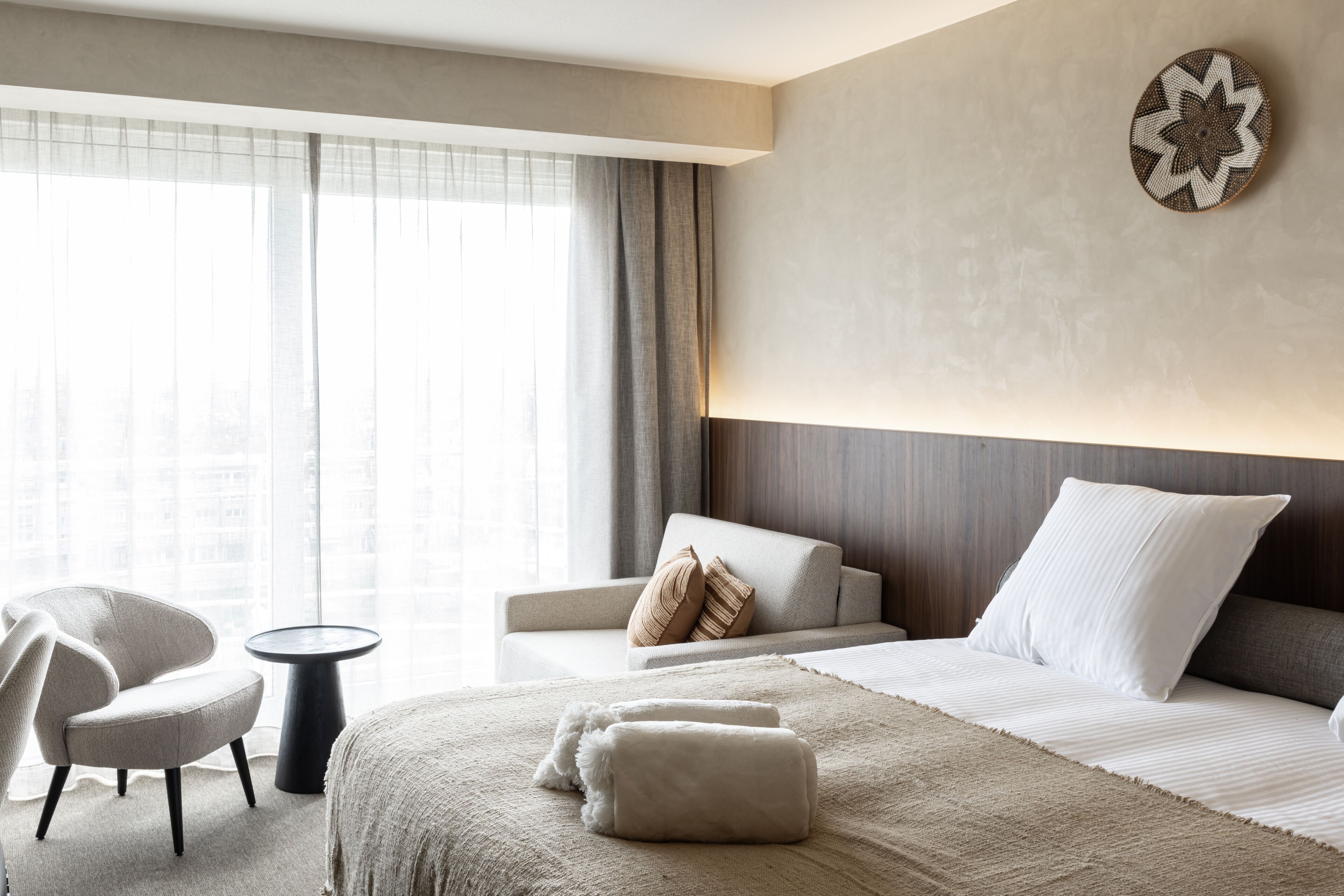 Una habitación de hotel moderna con una cama grande, un sofá, una silla y una mesita.