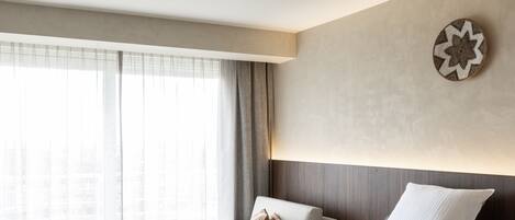 Una habitación de hotel moderna con una cama grande, un sofá, una silla y una mesita.