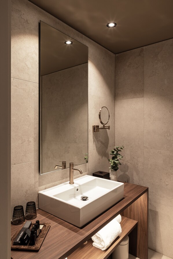Un baño moderno con un lavabo rectangular grande, un espejo y un mueble de tocador de madera.