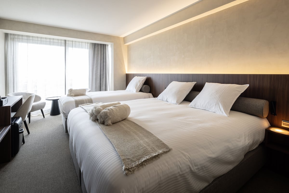 Habitación de hotel con dos camas, un escritorio y una silla.