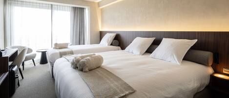 A hotel room with two beds, a desk, and a chair.