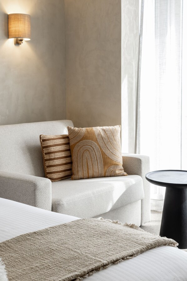 A modern hotel room with a sofa, two patterned pillows, a side table, and a lamp. - Beach Palace Hotel by CW Hotel Collection (Blankenberge)